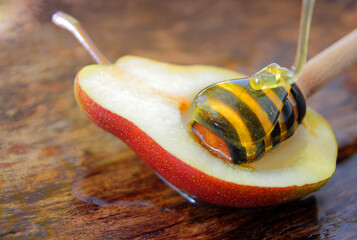 
pears on a wooden plate with natural honey and honey dipper.