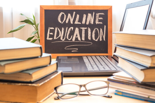 Chalk board - online learning, computer and a stack of books. Remote education concept.