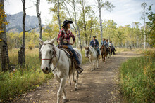 Female Rancher Leading Horseback Ride On Idyllic Autumn Ranch Trail