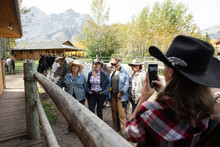 Rancher Photographing Women Friends Preparing For Horseback Ride