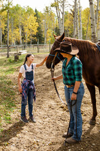 Female Rancher And Girl With Horse In Autumn Ranch Paddock