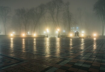 Poster - Alley of a night winter park in a fog. Footpath in a fabulous winter city park at night in fog with benches and latterns. Beautiful foggy evening in the Mariinsky Park. Kyiv, Ukraine.