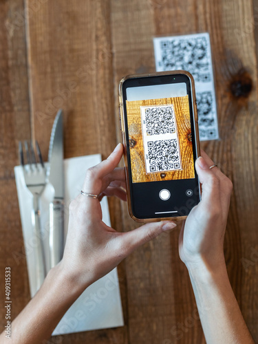 Young woman hands using the smart phone to scan the qr code to select food menu in the restaurant.