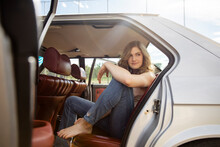 Beautiful Barefoot Teenage Girl Sitting In Back Seat Of Open Car Door