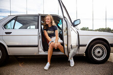 Happy Teenage Girl Sitting In Open Car Doorway