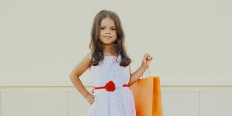 Wall Mural - Portrait of smiling little girl child with shopping bags on city street