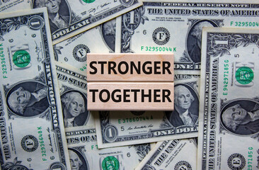 Wall Mural - Stronger together symbol. Concept words 'stronger together' on wooden blocks on a beautiful background from dollar bills. Business, motivational and stronger together concept.