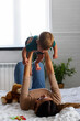 © lordn - Smiling mother playing with her cute toddler son at home in the bed. Playing with children.