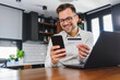 © lordn - Young man holding credit card sitting in front of laptop computer at home paying for online order. People lifestyle modern technologies and e-commerce concept. Online banking and shopping