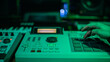 The hands of an artist creating music with his drum machines under green light.