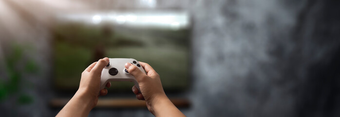 Fototapete - controller in the hands of man playing video games in the living room