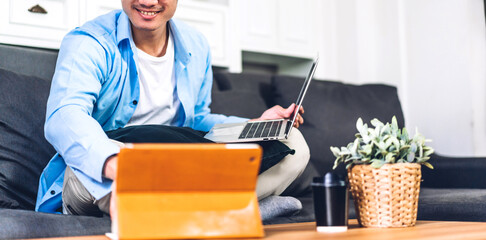 Wall Mural - Young smiling asian man using laptop computer working and video conference online meeting with colleagues at home.Young creative man use tablet.work from home concept