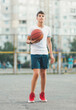 © Natali - Cute young boy plays basketball on street playground in summer. Teenager in white t shirt with orange basketball ball outside. Hobby, active lifestyle, sport activity for kids.
