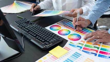 Poster - graphic designer team working on web design using color swatches editing artwork using tablet and a 