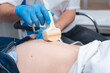 © salomonus_ - The young doctor makes an ultrasound of the abdominal cavity to a young beautiful girl. Ultrasound pregnancy