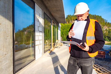 Poster - the engineer carefully examines the construction documentation. a man next to a building under const