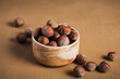 Pile of hazelnuts filbert in a bowl on a brown background. Fresh nuts in their shells.
