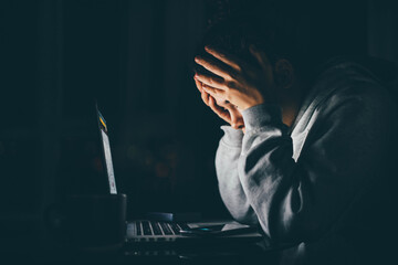 Bored woman sitting near laptop, working from home at the night.