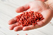 © Lubo Ivanko - Young man hand with dried goji berries over white boards desk, closeup detail