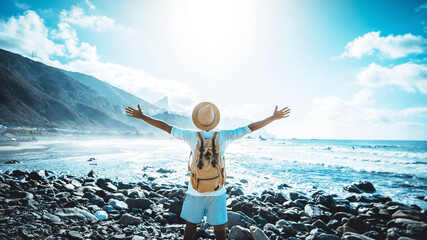 Wall Mural - Happy man with arms up enjoying freedom on the beach - Hiker with backpack celebrating success outdoor - Blue filter