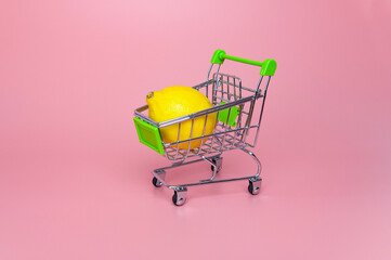 lemon in supermarket trolley on pink background