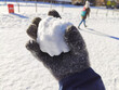 Snowball in a gloved hand in a snowball fight with people in the background