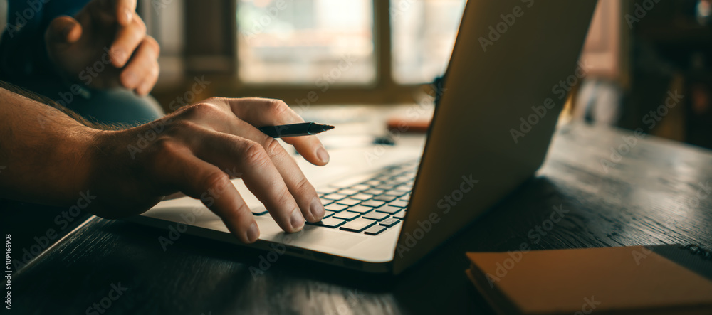 Close-up of male hands with laptop. Man is working remotely at home. Freelancer at work - obrazy, fototapety, plakaty 