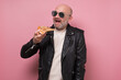 © Viktor Koldunov - Cheerful mature guy eating a pizza slice isolated on pink background