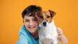 Portrait of happy smiling boy and dog Jack Russell Terrier hugs her with tenderness and look at camera on yellow background. Pets. Emotions of people. Childhood. Life style. Pet care