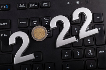 black keyboard. close-up. on it are laid out numbers of metal 2022 in the center of the coin 2 euro