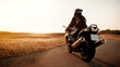 © Aleksandr - Handsome motorcyclist in leather jacket and helmet at sunset on the road in warm sun rays
