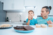 © goami - happy kid boy and father eating healthy peanut butter toast at home kitchen