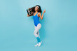 African fitness girls showing peace sign on blue background. Studio shot of shapely female model in aerobics form holding boombox.