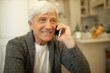 © Anatoliy Karlyuk - Indoor image of happy gray haired mature male in elegant cardigan sitting at home, holding mobile at ear, having phone conversation with daughter , smiling, receiving good news. Gadgets and aging