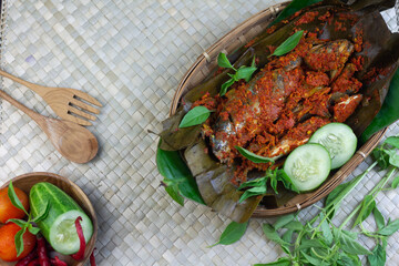 Pepes Ikan Layang or Pais Ikan or Steamed mackerel fish, typically Indonesian traditional food made from fish, spices, wrapped with banana leaves and steamed. Dark Wooden background. 