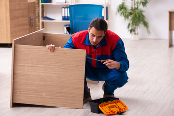 Wall Mural - Young male contractor repairing furniture in the office