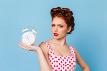 Upset Woman With Bright Makeup Showing Time. Studio Shot Of Beautiful Pinup Girl With Clock.