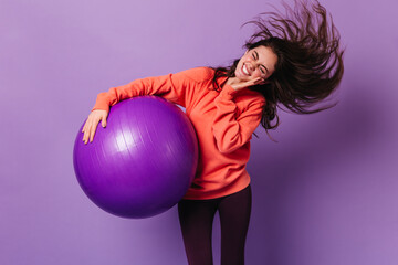 Wall Mural - Nice girl shakes her head vigorously while holding fitball. Emotional joyful woman doing aerobics