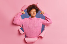 Self Assured Beautiful Young Afro American Woman Raises Arms Shows Biceps Being Strong And Powerful Proud Of Her Own Achievements Wears Casual Knitted Sweater Breaks Through Paper Background