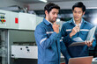 © whyframeshot - Male Asian caucasian engineer professional having a discussion standing consult at machine in the factory ,two expert coworker brainstorm explaining and solves the process of the cnc operate machine
