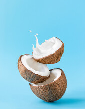 Cracked Coconut With Splashes Of Milk On Blue Background