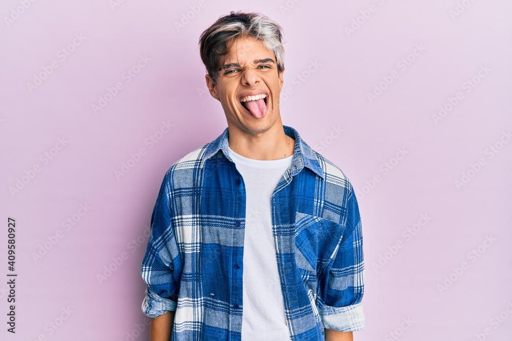 Young hispanic man wearing casual clothes sticking tongue out happy with funny expression. emotion concept.