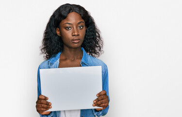 Beautiful african young woman holding blank empty banner thinking attitude and sober expression looking self confident