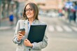 © Krakenimages.com - Young hispanic businesswoman drinking coffee holding binder at the city.