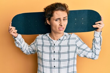 Poster - Young brunette woman holding skate clueless and confused expression. doubt concept.