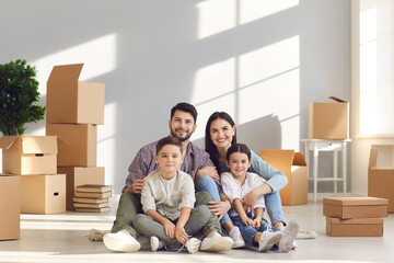 Buying new apartment and real estate for family concept. Happy family with son and daughter sitting together on floor and hugging together feeling positive with relocating to new home