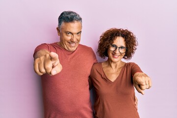 Wall Mural - Beautiful middle age couple together wearing casual clothes pointing to you and the camera with fingers, smiling positive and cheerful