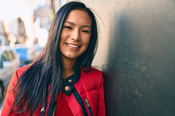 Wall Mural - Young latin woman smiling happy leaning on the wall at the city.