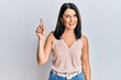 © Krakenimages.com - Middle age brunette woman wearing casual clothes smiling with an idea or question pointing finger up with happy face, number one