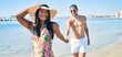 © Krakenimages.com - Young latin couple wearing swimwear  smiling happy walking at the beach.